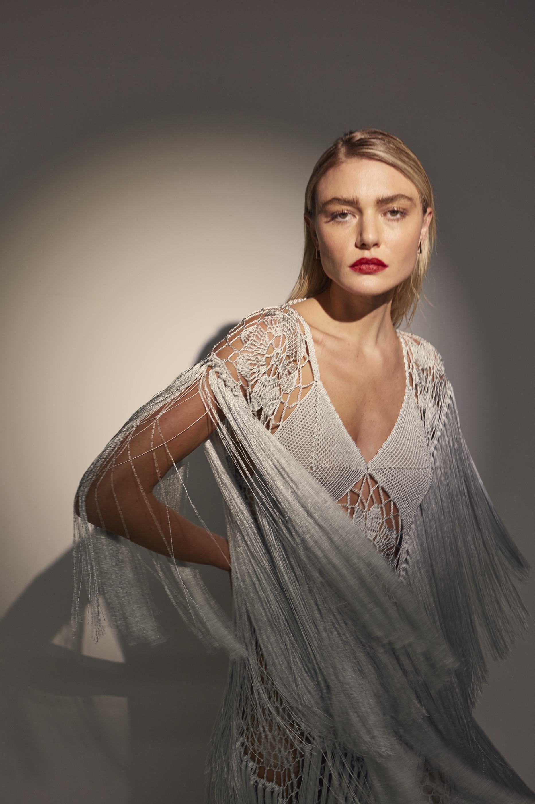 Blonde model in a silver fringed knit look under direct studio light