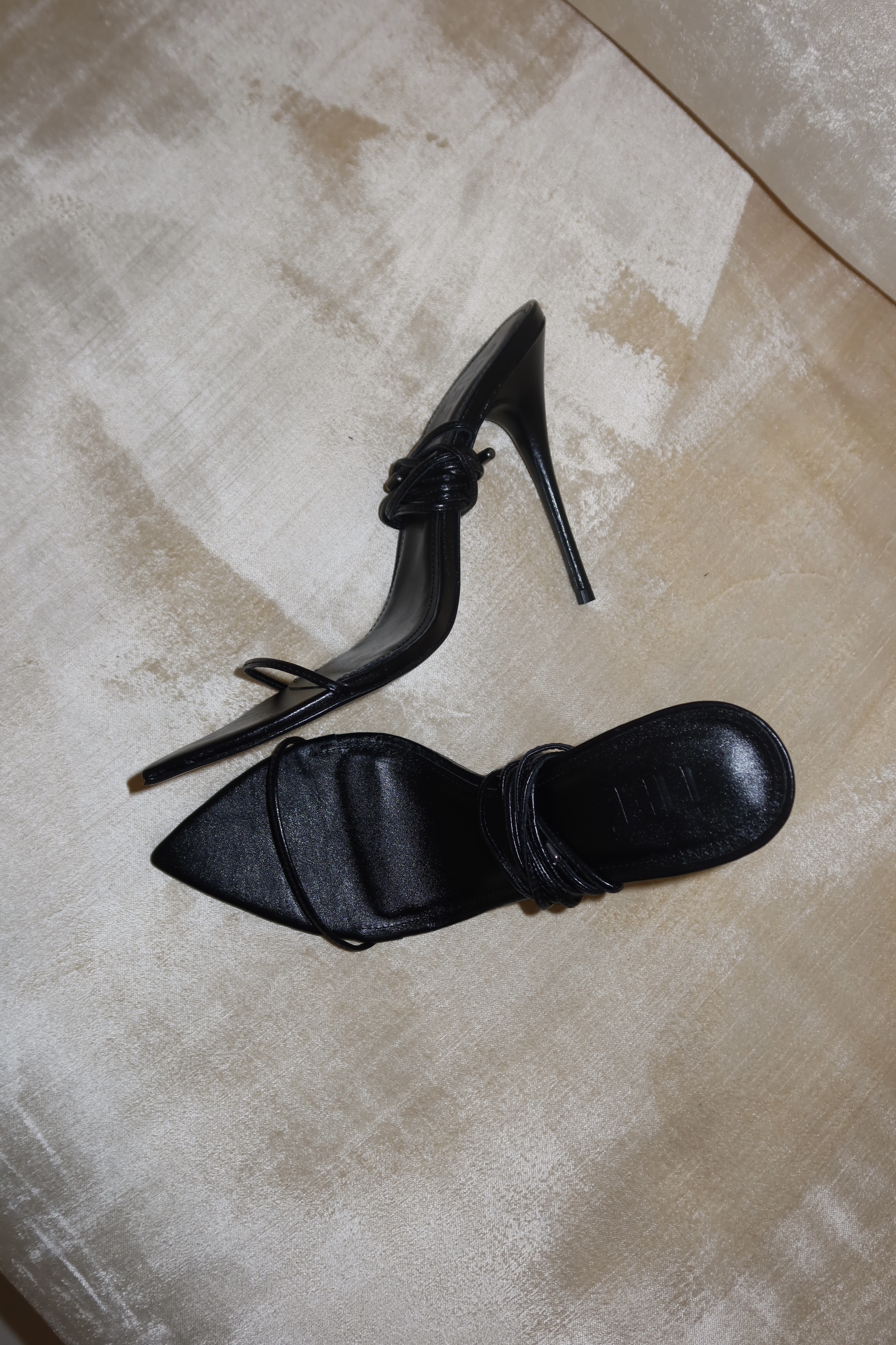 Black Tift sandals photographed on light fabric